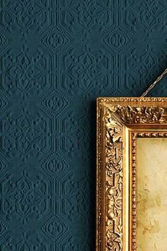 an image of a gold frame hanging on the wall next to a blue wallpaper