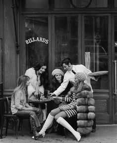 a group of people sitting around a table in front of a building