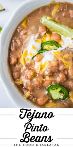 a white bowl filled with beans and topped with sour cream, jalapenos