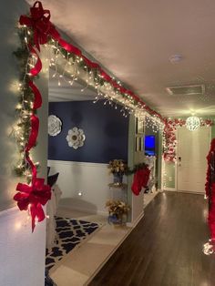 a hallway decorated for christmas with red bows and lights on the wall, along with other decorations