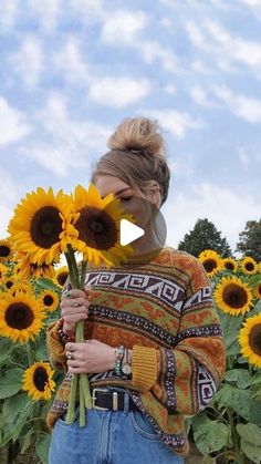 a woman standing in front of a field of sunflowers with her face close to the camera