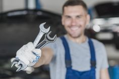 a man holding up a wrench in front of a car