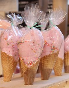 ice cream cones with pink frosting and sprinkles wrapped in plastic bags