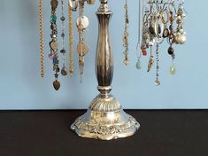 a silver lamp with many different necklaces hanging from it's sides on a table