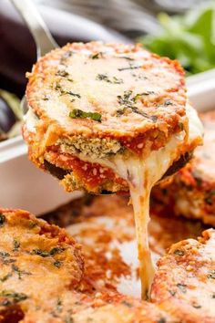 a fork full of lasagna sauce being lifted from a casserole dish