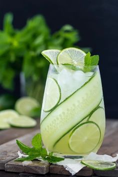 a glass filled with cucumber and limeade on top of a wooden table