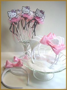 hello kitty cake toppers in a glass vase with pink bows on the stems and ribbon