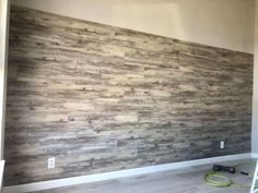 an empty room with wood paneling on the wall and a ladder in front of it