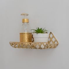 a gold shelf with a potted plant and a soap dispenser