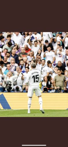 a man standing on top of a field next to a soccer ball in front of a crowd