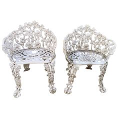 a pair of white metal chairs sitting next to each other on top of a table