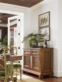 a dining room table and chairs in front of a door with plants on the side