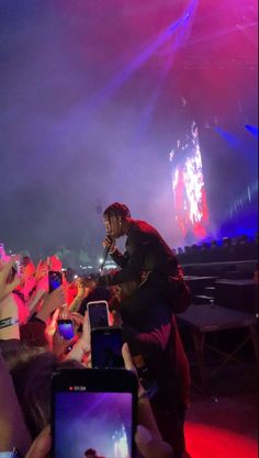 a man standing on top of a stage next to a group of people holding up cell phones