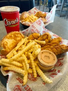 fried chicken, french fries and coleslaw on a table with a can of soda