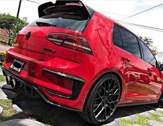 the rear end of a red car parked on top of a stone walkway in front of a house