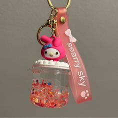 a pink keychain with an animal on it and some beads in the jar