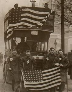 an old black and white photo shows men carrying the american flag on a double decker bus