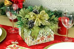 a christmas centerpiece with pine cones and greenery sits on a red table cloth