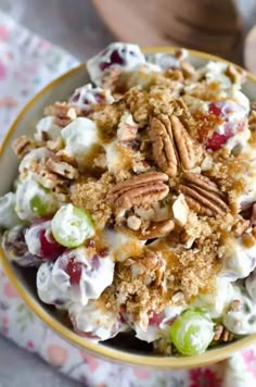 a close up of a bowl of food with grapes and pecans in it on a table