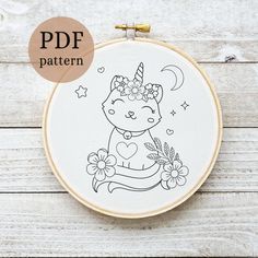 an embroidery pattern with a cat wearing a unicorn hat and holding a flower in its hand