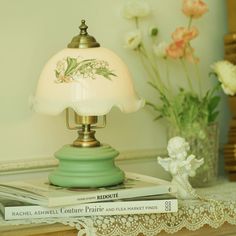 a lamp sitting on top of a table next to flowers