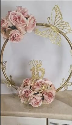 pink flowers are in the middle of a gold wreath