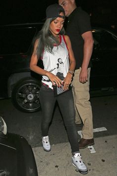 a man and woman are standing next to each other in front of a car at night