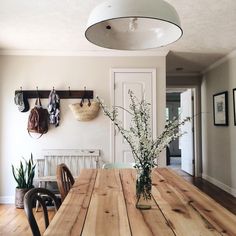 a wooden table sitting in the middle of a room next to a white door and potted plant