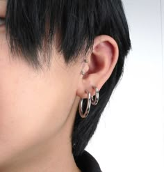 a woman with black hair wearing large silver hoop earrings