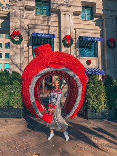 a woman is walking in front of a giant red object