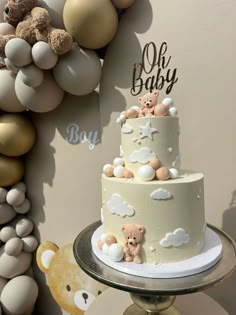 a baby shower cake with teddy bears on top and balloons in the background for decoration