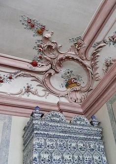 an ornately decorated ceiling with flowers and leaves painted on the wall above it, along with other decorative items