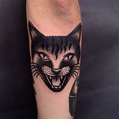 a black and white cat tattoo on the left leg with an arrow in it's mouth