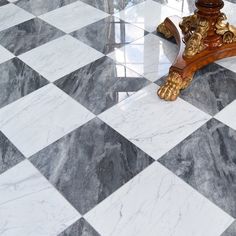 a marble floor with an ornate wooden stand on it's side and black and white checkered tile