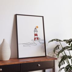 an art work is displayed next to a table with a vase and potted plant