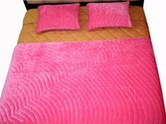 a bed with pink sheets and pillows on it