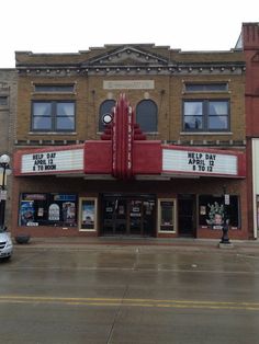 an old movie theater with cars parked in front