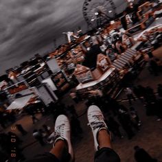 a person standing in front of a ferris wheel with their feet up on the ground