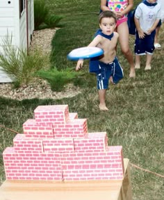 two children playing with a frisbee in the yard while another child looks on