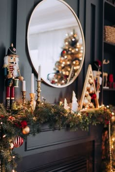 Black chimney decorated with a pine leaves garland and Christmas decorations. It has a touch of red. It has two standing nutcrackers and a mirror on the wall. Candles. And a small Christmas tree. Fruit Garland, Christmas Decor Inspiration, Christmas Tablescape, Christmas Interiors, Christmas Inspo, Wreath Tutorial, Christmas Mantels, Mesh Wreath