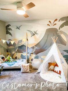 a child's bedroom with a teepee tent on the floor and birds painted on the wall