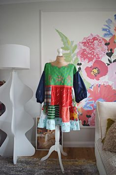 a dress on a mannequin in front of a floral wallpapered room