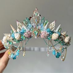 a close up of a person holding a tiara with seashells on it