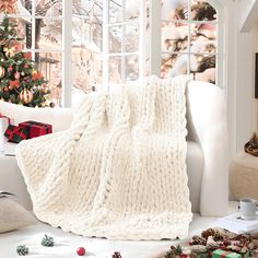 a white couch with a blanket on it next to a christmas tree