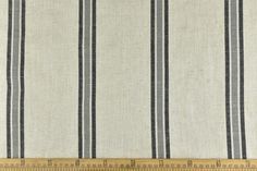 a ruler is measuring the width of a fabric with vertical stripes on it, which are white and blue