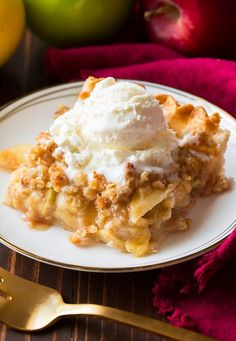 a piece of pie on a plate with ice cream and apples in the back ground