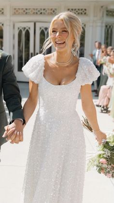 a bride and groom holding hands as they walk down the aisle