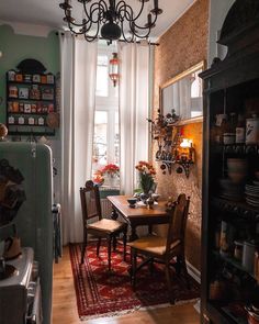 a dining room table and chairs in front of a window with a chandelier