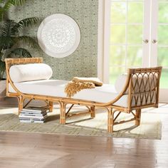 a bamboo chaise lounger with white cushions in front of a green wallpapered room