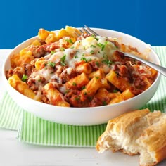 a white bowl filled with pasta and meat on top of a green and white towel